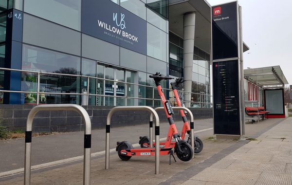 Photo of rental scheme e-scooters parked at a MetroBus stop.