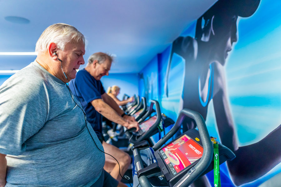 Members working out on state-of-the-art Technogym treadmills at Active gym. Photo of people working out on a line of treadmills in a gym.