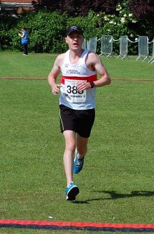 Ciaran McQuade crosses the finish line in the Bradley Stoke 10k Run 2015.