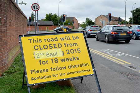Roadside sign announcing closure of Woodlands Lane for 18 weeks from 2nd September.