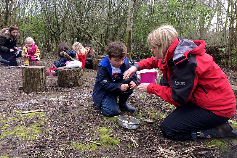 Photo of BSCS Catkins class learning in the forest school area.