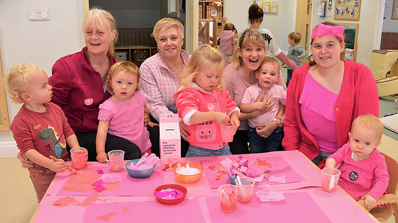 Photo of staff and children at Happy Days Nursery enjoying an activity on their 'wear it pink' day.