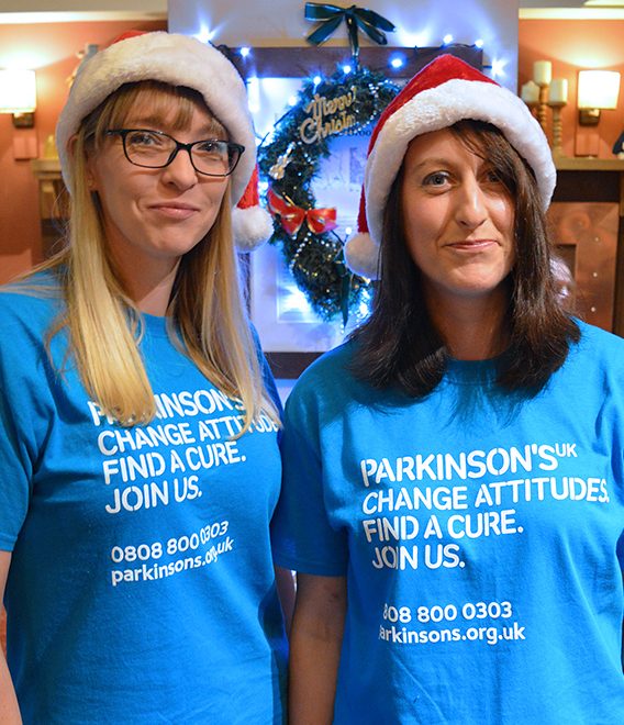 Photo of Karen Taylor (left) and Vicky Lovell in Santa hats and Parkinson's UK T-shirts.