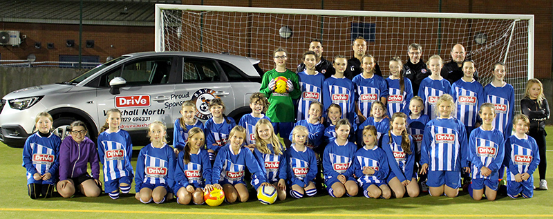 Photo of the girls' teams wearing match kit sponsored by Drive Vauxhall Bristol North.