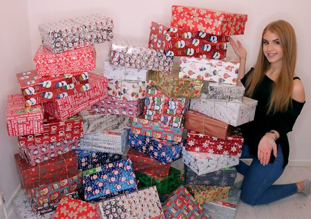 Photo of Ellie Harriss with the 44 shoeboxes she collected.
