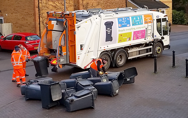 Photo of black refuse bins being collected.