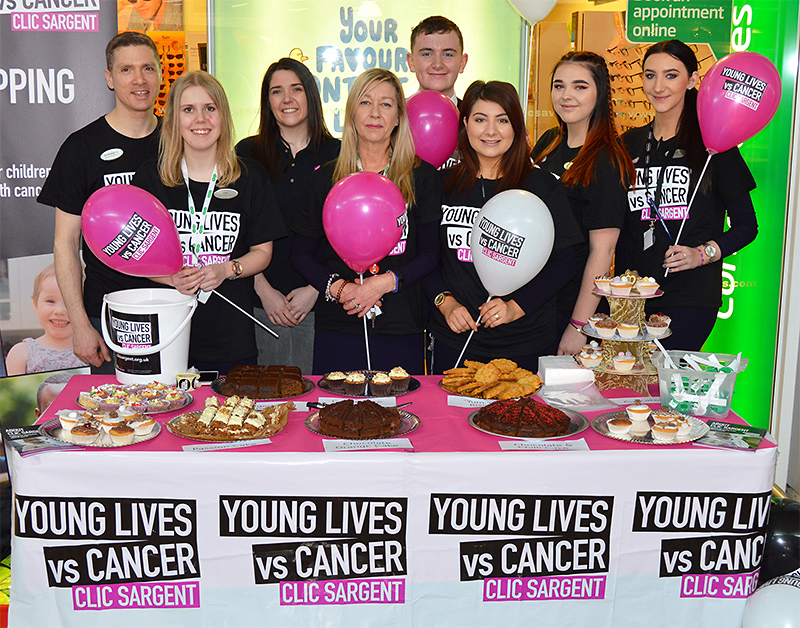 Photo of staff standing behind the cake sale stand outside the Specsavers store.