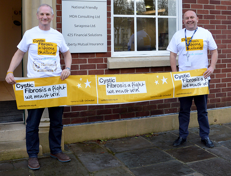 Photo of Neil Thompson and Wayne Carter holding a Cystic Fibrosis Trust banner outside the National Friendly office
