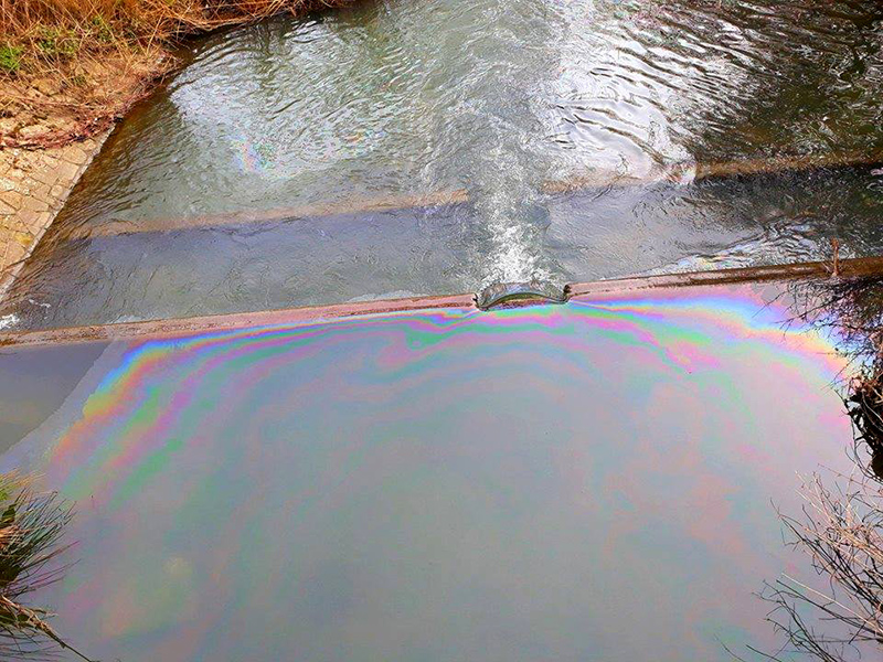 Photo showing a rainbow sheen on the surface of the water at one of the weirs on Stoke Brook.