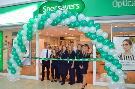 Photo of staff standing under a balloon arch at the entrance to the store.