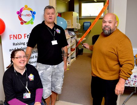 Photo of Gareth Chilcott cutting a ribbon to open the FND FrieNDs office, watched by Lucy Skinner and Kevin Clark.