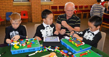 Photo of an instructor and three children at a session of the 'Scratch Code 4 Kids' code club.