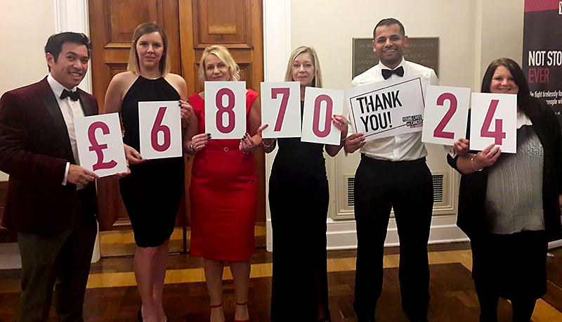 Specsavers staff hold up cards showing the amount they have raised for CLIC Sargent.
