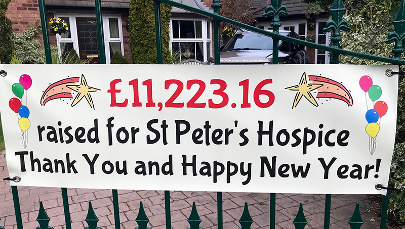 Photo of a banner hanging on a gate, announcing the final amount of £11,223 raised for St Peter's Hospice.