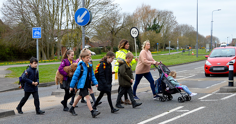 Esther Huke guides children and parents over the uncontrolled crossing point. Photo of Esther Huke guiding children and parents over the uncontrolled crossing point.