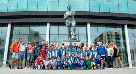 Photo of BSYFC U10 Blues team players, families and club officials grouped around the Bobby Moore Sculpture at Wembley Stadium.