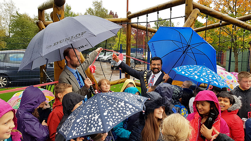Photo of Mayor Tom Aditya cutting a ceremonial ribbon to officially open the new play equipment.