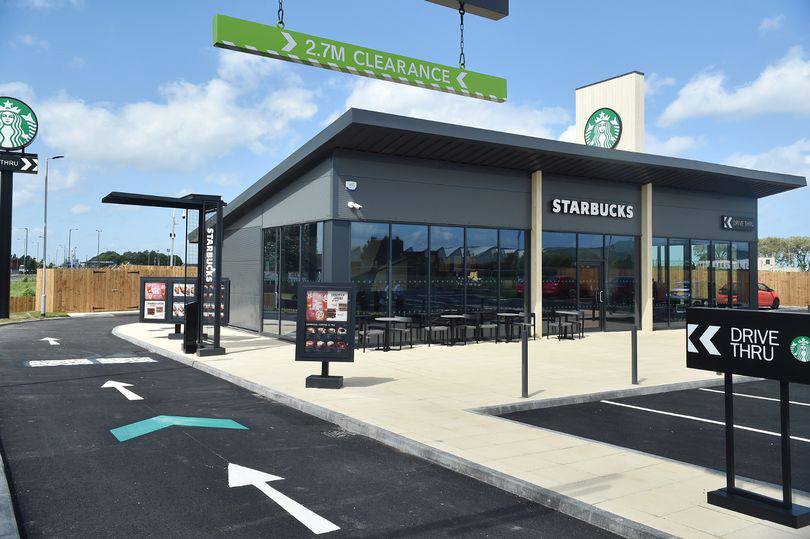 Photo of a single-storey Starbucks restaurant with drive-through lane.