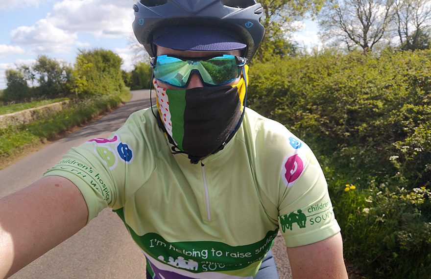 Photo of Rob Berry, wearing sun glasses and a face mask, on his bike.