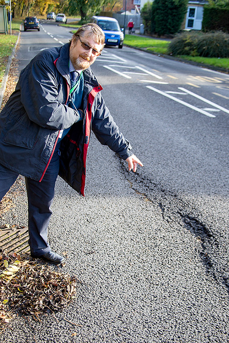Photo of Cllr Keith Cranney pointing out a damaged road surface.