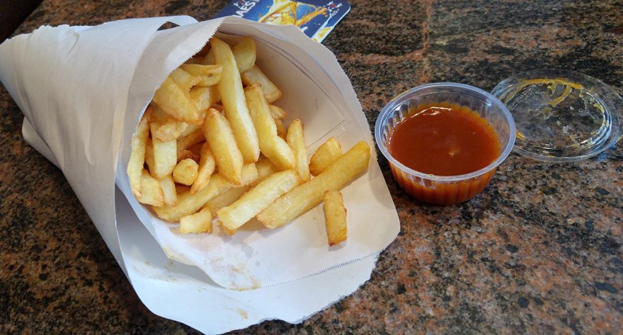 Photo of a bag of takeaway fries and a small dish of ketchup.