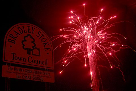 Photo of a noticeboard with a firework exploding in the background.