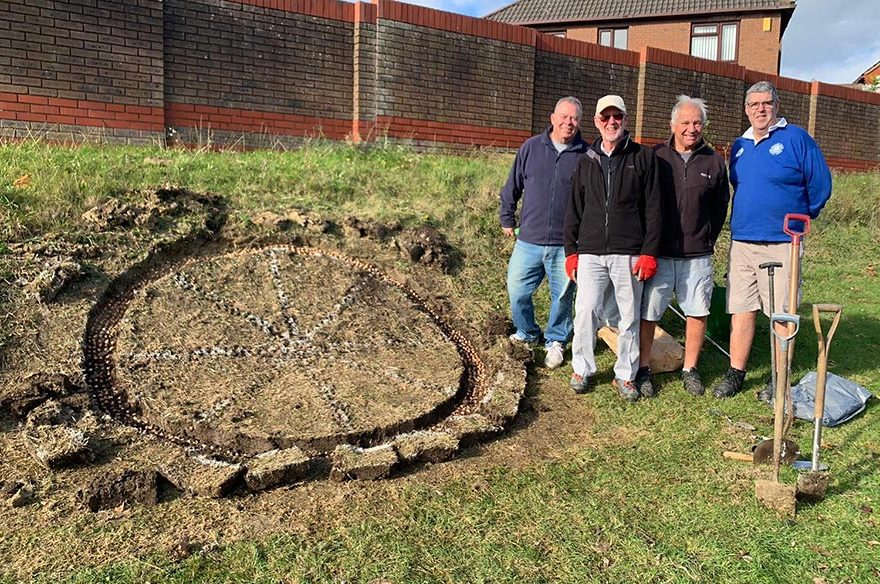 Photo of a group of people standing next to a bulb planting site.