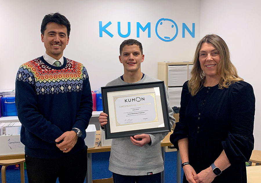 James Smith, a student at Kumon Bradley Stoke Study Centre, receives his Completion Award. Photo of a young person holding a certificate, with one adult to each side.