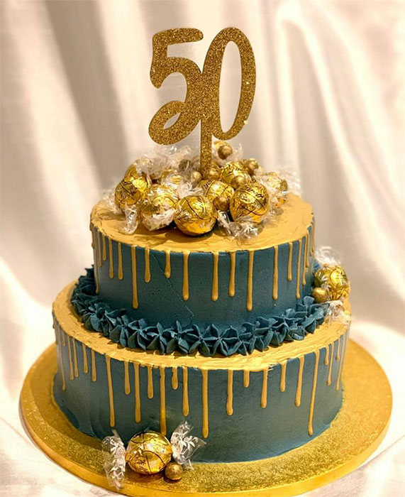 Photo of a 50th birthday cake in dark green and gold.