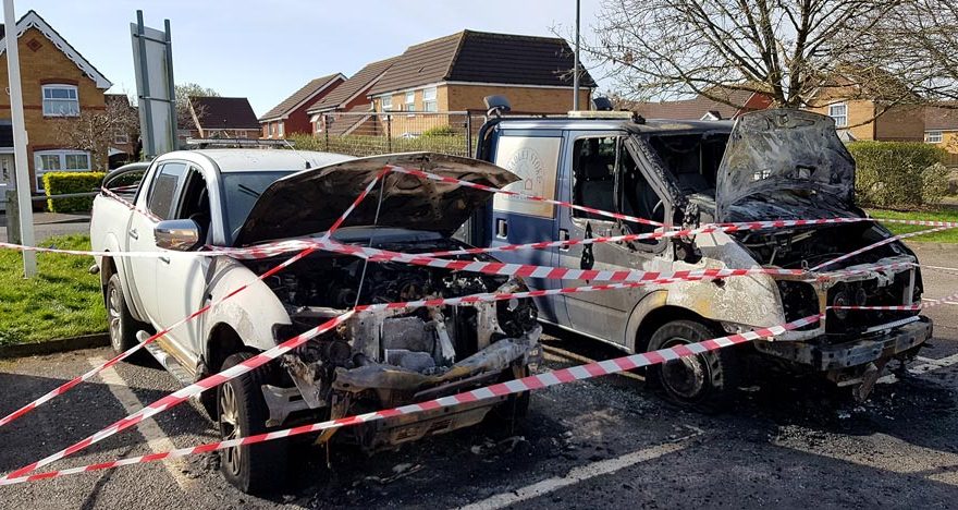 Photo of two fire-damaged trucks.