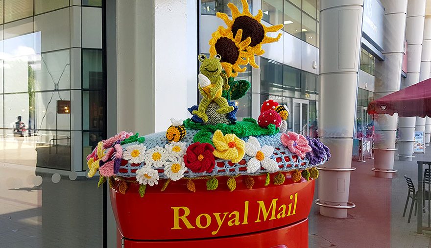 Photo of crocheted decoration on top of a red postbox.