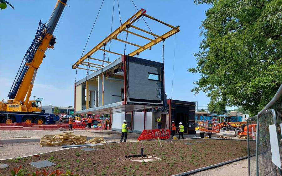 Photo of a crane lifting a modular building element.