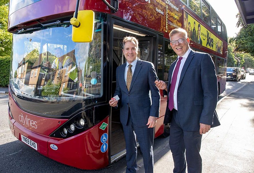 Photo of two men standing alongside a bus.