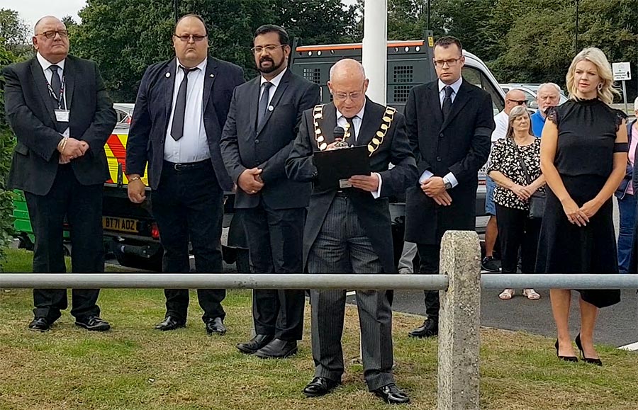 Local proclamation of the new monarch, King Charles III, by the mayor of Bradley Stoke, Cllr Tony Griffiths. Photo of a group of people in mourning attire, with one wearing a chain and speaking into a microphone.