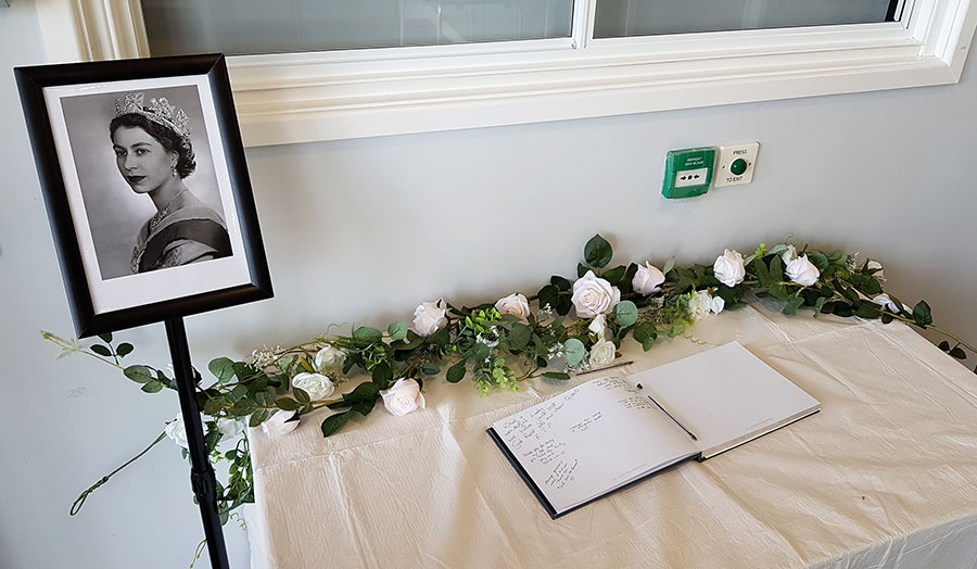 Book of condolence opened in memory of Her Majesty Queen Elizabeth II – at Little Stoke Community Hall. Photo of a book of condolence on a table, alongside a photo of HM Queen Elizabeth II.