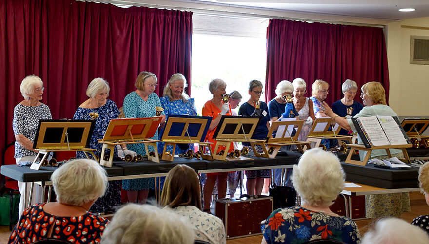 Photo of a line of women holding handbells.