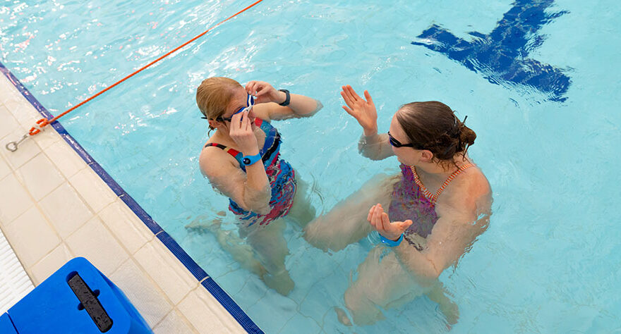 Photo of two women chatting in a swimming pool.