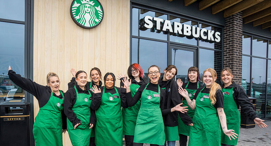 Photo of a group of employees standing outside a Starbucks restaurant.
