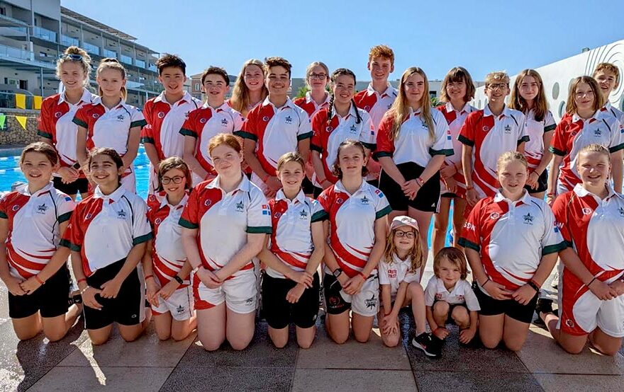 Photo of a large group of children beside a swimming pool.