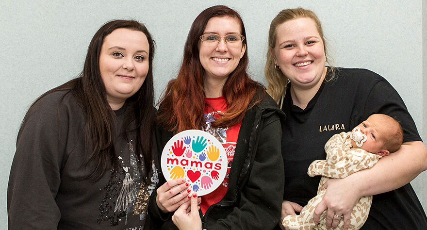 Photo of three women, one holding a baby.