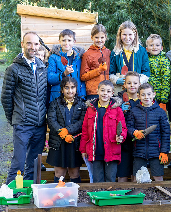 Photo of a teacher with a group of pupils in an outdoor setting.