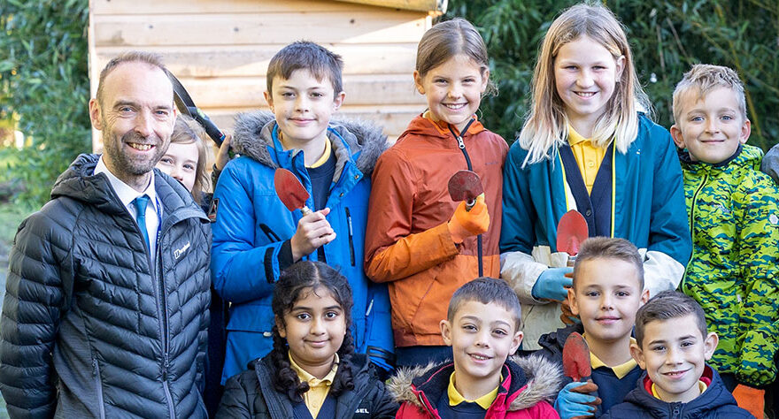 Photo of a teacher with a group of pupils in an outdoor setting.