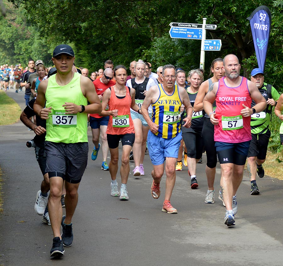 Photo of a large number of runners wearing race numbers and running along a path.