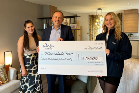 Photo of three people at a charity cheque presentation.