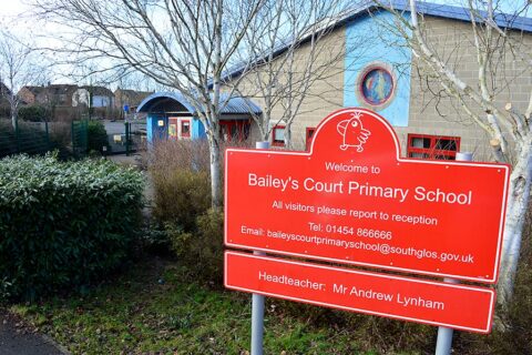 Photo of a red sign outside the entrance to a school.