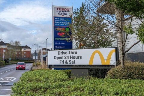 Photo of an advertising sign displaying: "Drive-thru open 24 Hours Fri & Sat".